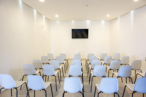a room with white chairs and a tv on a wall at Ariadne Beach - Adults Only in Agios Nikolaos