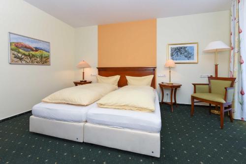 een hotelkamer met een bed en een stoel bij Apartments im Nordseegartenpark in Bensersiel