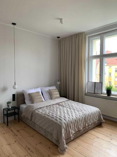 a white bedroom with a large bed and a window at Apartament Haffnera in Sopot