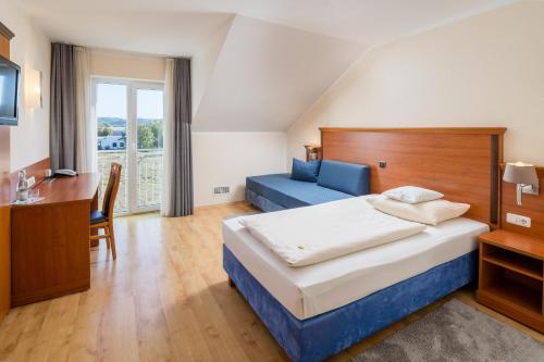 Habitación de hotel con cama, escritorio y sofá en Hotel Meridian ***superior, en Landshut