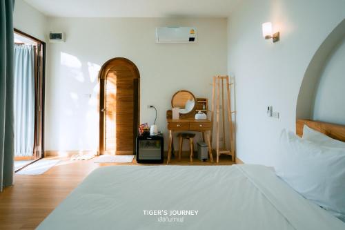 a bedroom with a bed and a table in a room at Arabica Lodge (อาราบิก้า ลอดจ์) in Ban Huai Khai