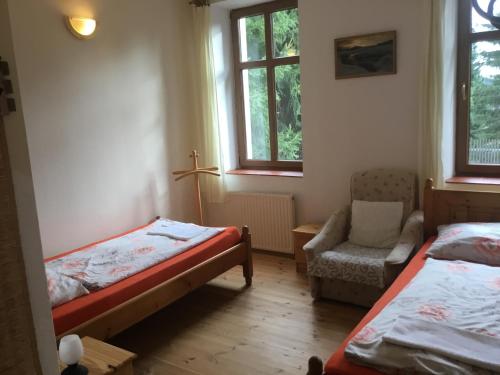 um quarto com 2 camas e uma cadeira e janela em Penzion Real em Bedřichov