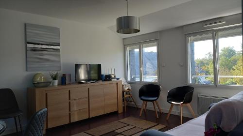 - un salon avec une télévision sur une commode et 2 chaises dans l'établissement Au calme, avec jardin et proches des sites touristiques, à Vannes
