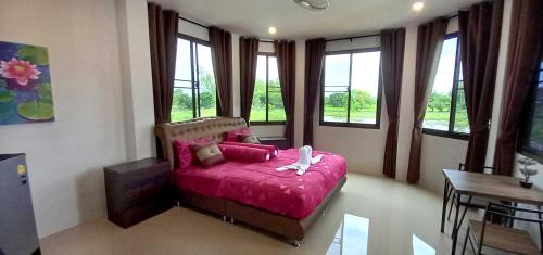 a bedroom with a pink bed in a room with windows at Bua Daeng Homestay Resort in Amphoe Kumphawapi