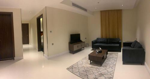 a living room with a couch and a tv at حيات الفرسان الفندقية in Al Qurayyat