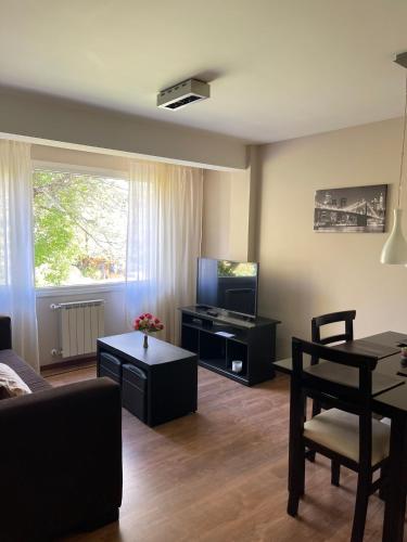 sala de estar con sofá, TV y mesa en Apartamento Céntrico, ideal p/ pareja de viajeros en San Carlos de Bariloche