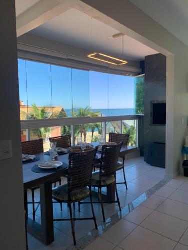 a dining room with a table and chairs and a large window at BORBOLETAS DO MAR in Bombinhas