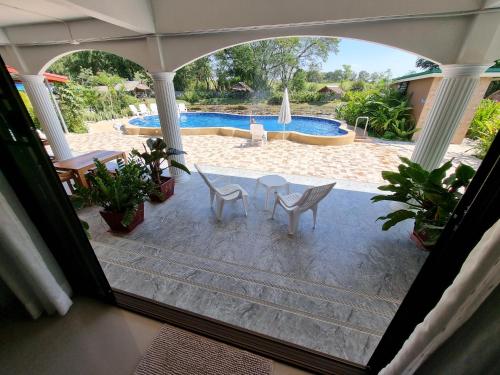 a patio with a table and chairs and a pool at Bua Daeng Homestay Resort in Amphoe Kumphawapi