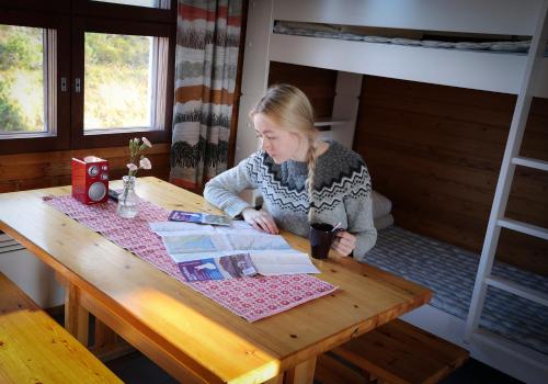a woman sitting at a wooden table in a room at Kilpisjärven Retkeilykeskus Cottages in Kilpisjärvi