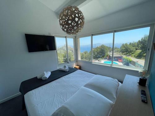 ein Schlafzimmer mit einem großen Bett und einem großen Fenster in der Unterkunft Villa Caiou/ vue Mer/ Piscine/Jardin in Le Rove