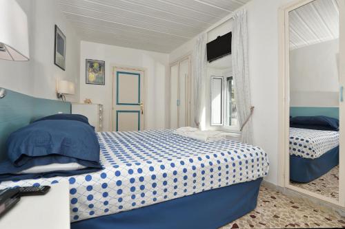 um quarto com uma cama azul e branca e um espelho em Maison Lucienne em Minori