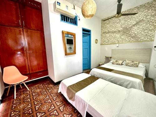 a room with two beds and a chair in it at Hotel Kasaya Real in Santa Marta