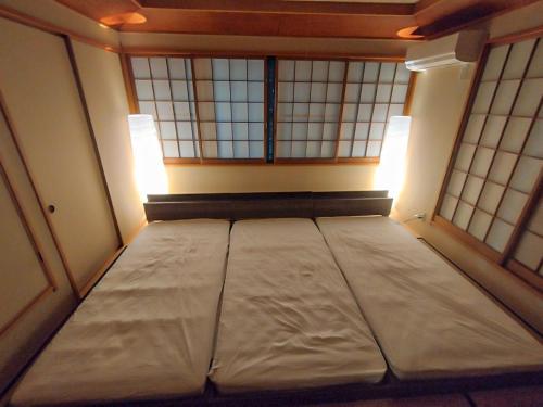 a large bed in a room with two windows at R House 川越 in Kawagoe