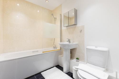 een badkamer met een wastafel, een toilet en een bad bij The Colindale Collection in Colindale