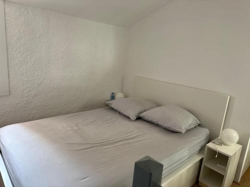a white bed with two pillows in a bedroom at Collioure, bel appartement de 40m2 avec balcon et parking in Collioure