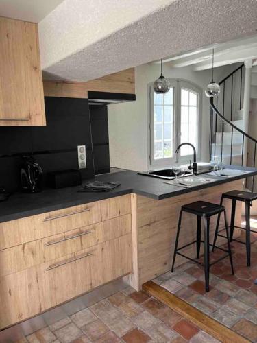 une cuisine avec un évier et un comptoir avec des tabourets dans l'établissement Maison d'hôtes Au Petit Lavoir, à Ymeray