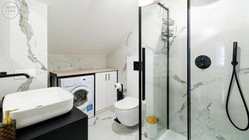 a bathroom with a shower and a toilet and a washing machine at Apartamenty Good Time - Hugo Apartments - blisko centrum in Szklarska Poręba