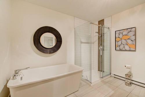 a white bathroom with a tub and a shower at Nouveau - Chalet moderne - Spa, piscine & sauna! in Pont-Rouge