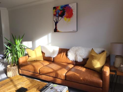 a brown leather couch in a living room with a table at Cocoa River - Quiet city centre, close to the Shambles, on the river, two bed, two bath, allocated parking in York