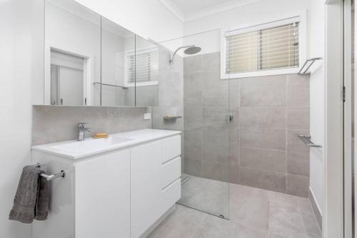 een witte badkamer met een wastafel en een douche bij 100 Paces in Broadwater