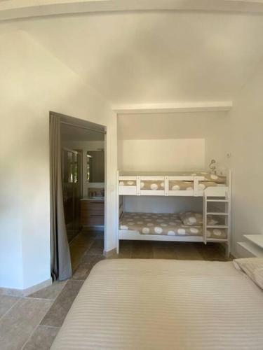 Cette chambre blanche comprend un lit et un miroir. dans l'établissement Appartement de charme près d'Uzès, à Saint-Siffret