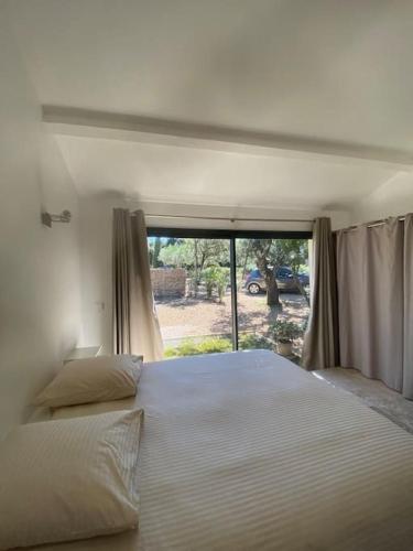 une chambre avec un grand lit blanc et une fenêtre dans l'établissement Appartement de charme près d'Uzès, à Saint-Siffret
