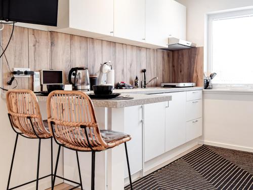 a kitchen with white cabinets and two bar stools at M&M Studio's 1 & 2 in Zandvoort