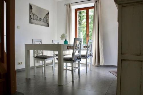 a dining room with a white table and chairs at Le 43, Gîte rural dans la vallée de la Sambre. in Merbes-le-Château