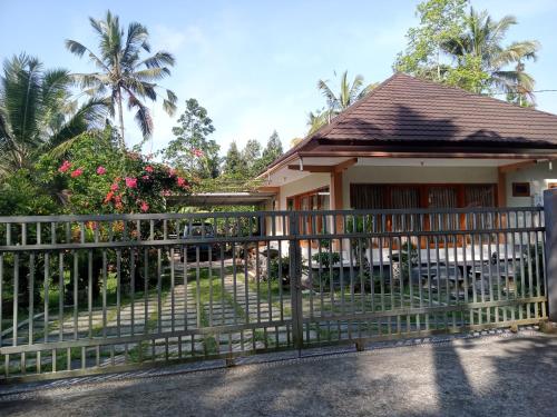 a fence in front of a house with palm trees at umah kampung bendul in Penebel