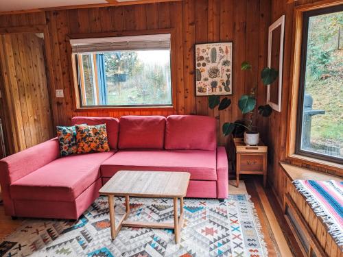 a living room with a pink couch and a table at Nettledown Farms Bed & Breakfast in Salt Spring Island