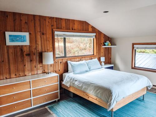 1 dormitorio con 1 cama y pared de madera en Nettledown Farms Bed & Breakfast, en Salt Spring Island