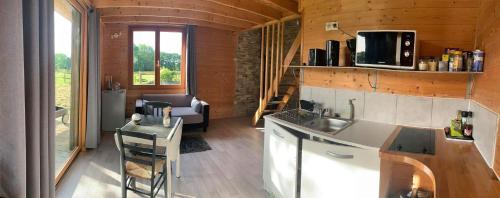 eine Küche und ein Wohnzimmer eines winzigen Hauses in der Unterkunft Le chalet de la Champagne in Saint-Molf