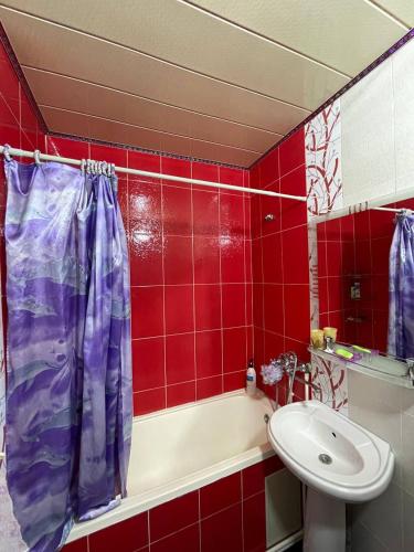 La salle de bains est pourvue d'une baignoire, d'un lavabo et de carreaux rouges. dans l'établissement 3х комнатная квартира, à Samarcande