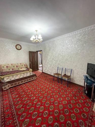 Cette chambre comprend un lit, une télévision et un tapis rouge. dans l'établissement 3х комнатная квартира, à Samarcande