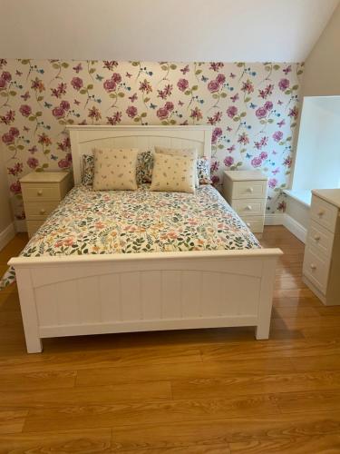 een slaapkamer met een wit bed met bloemenbehang bij Glenwood House Farm in Knightstown