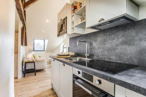 a kitchen with white cabinets and a sink at Beau L.O.F.T. sous les toits - vue sur mer 2 à 4 personnes - Résidence la Vague in Houlgate