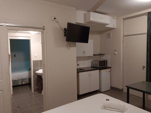 Katherine River Lodge في كاثرين: غرفة مع مطبخ مع تلفزيون على الحائط