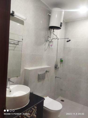 a bathroom with a sink and a toilet and a mirror at Hotel Mahadev Rishikesh in Rishīkesh