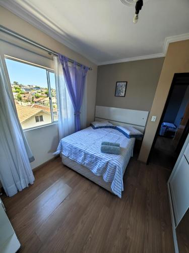 a bedroom with a bed and a large window at Apartamento completo em Joinville no Costa e Silva - Há 50 km das Praias SC in Joinville