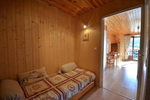 - une chambre avec un lit dans une pièce dotée de murs en bois dans l'établissement Duplex 59m2 - proche centre - balcon plein sud, à Corrençon-en-Vercors