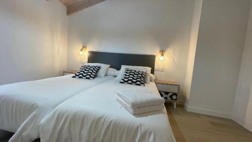 a bedroom with a white bed with black and white pillows at APARTAMENTOS AREKORATAS 255 y 256 in Muro de Ágreda
