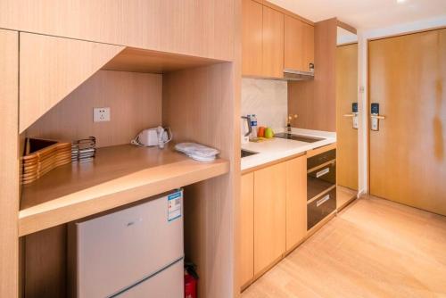 a kitchen with wooden cabinets and a white refrigerator at Guangzhou YuXiang Apartment - Guangzhou Pazhou International Convention and Exhibition Center in Guangzhou