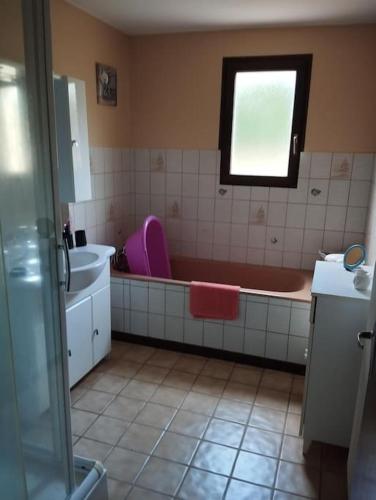een badkamer met een bad, een wastafel en een raam bij Maison de montagne in Bussang