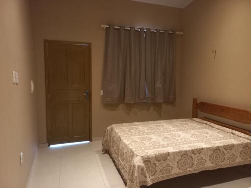 a bedroom with a bed and a window and a door at Pousada Rio e Mar in Fortim