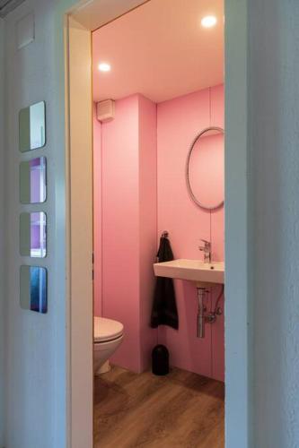 a pink bathroom with a toilet and a sink at Casa Alpsu in Sedrun