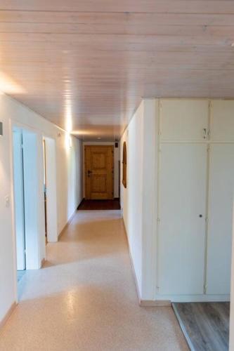 an empty hallway with white walls and a wooden door at Casa Alpsu in Sedrun