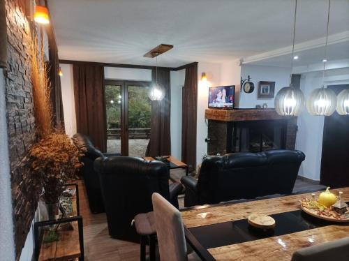 Vila KTM Lisine في ديسبوتوفاتس: غرفة معيشة مع كراسي جلدية سوداء ومدفأة