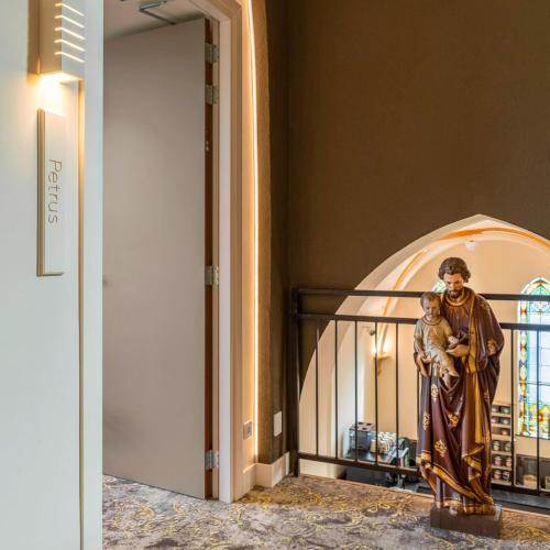 a statue of a woman holding a child in a room at KerkHotel Biervliet in Biervliet