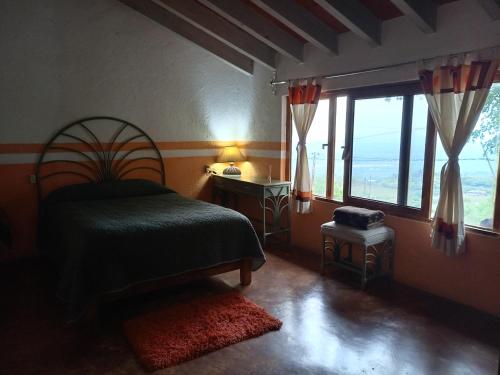 ein Schlafzimmer mit einem Bett und einem großen Fenster in der Unterkunft Casa los Olivos in Tepoztlán