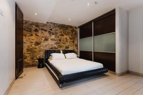 a bedroom with a bed and a brick wall at Casa Azul - Apartamento de 2 Pisos, 2Hab con Rooftop en Casco Antiguo in Panama City